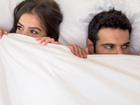 Portrait of a scared couple in bed with man and woman looking very anxious