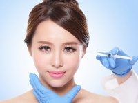 Close up of cosmetic injection to the pretty woman face. Isolated on blue background, asian