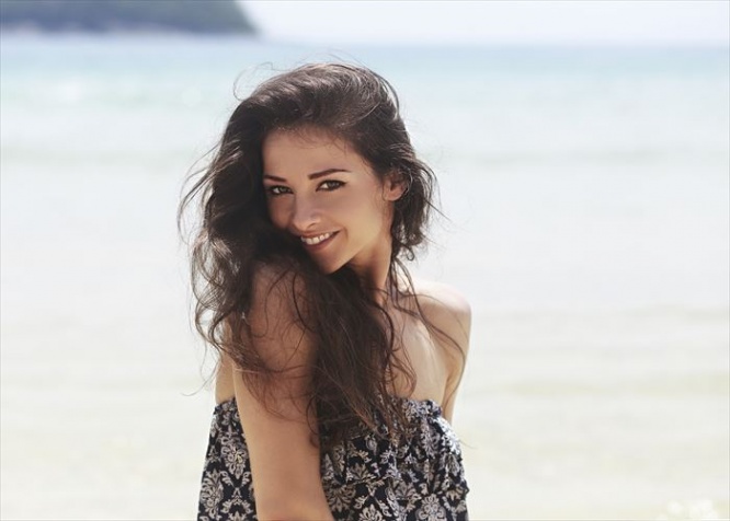 Beautiful toothy smiling woman joying on blue sea background