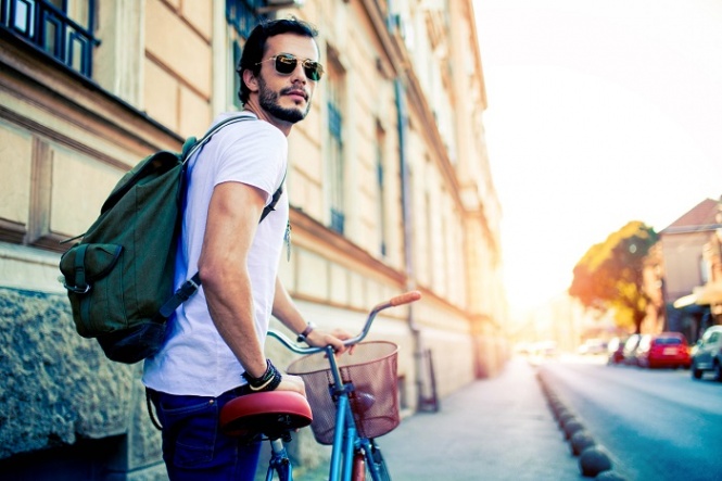 Handsome Man sitting on his Vintage Bike.Hipster bike rides by city.Hipster exploring the city by bike.