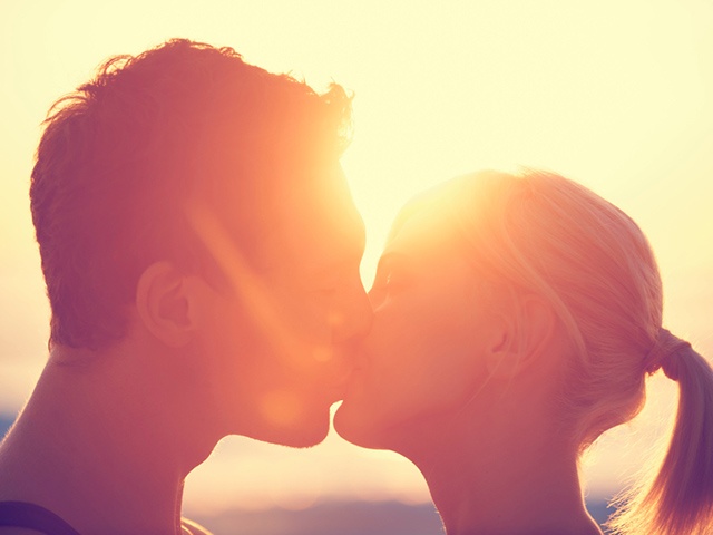 Young couple kissing each other at sunset.