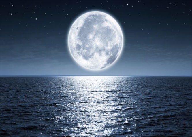 Full moon rising over empty ocean at night with copy space