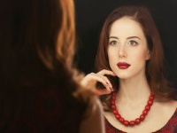 Portrait of a beautiful woman as applying makeup near a mirror.