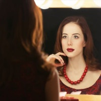 Portrait of a beautiful woman as applying makeup near a mirror.