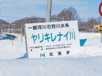 これは「やりきれない」な...　「ヤリキレナイ川」の看板、雪に埋もれてしまう