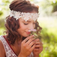 Boho teenager in a sunlit summer park serenely smelling a small pink daisy flower, her eyes closed with pleasure
