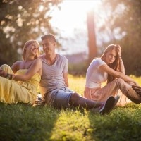 Happy couple talking to each other while young woman is depressed because the man didn't choose her.