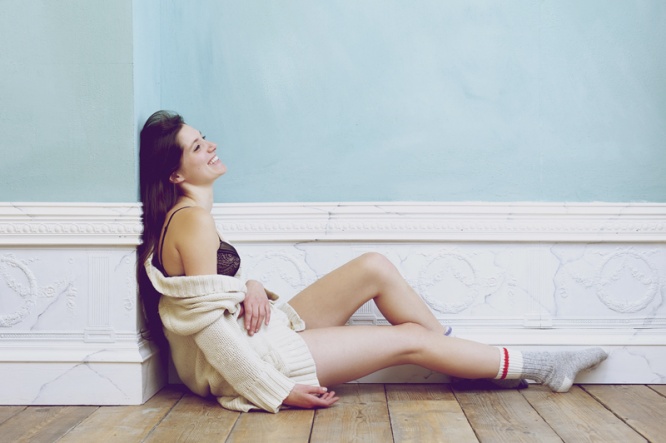 Smiling woman sitting on floor alone with underwear and sweater