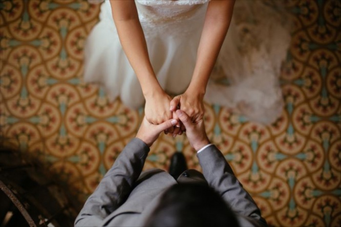 A close up shot of a bride and groom holding hands from a top view.