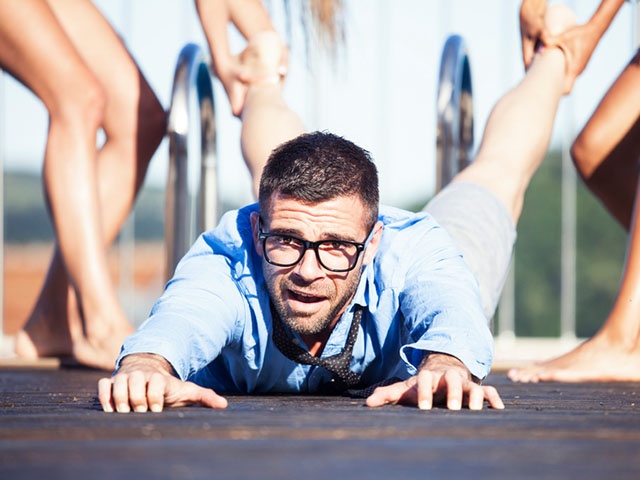 Women dragging a man on pool deck