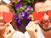 A picture of a young romantic couple covering eyes with hearts