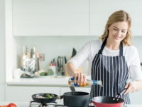 Happy woman cooking at home wearing an apron - healthy eating concepts