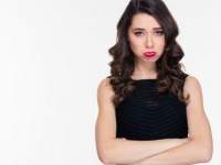 Cute offended sad curly girl with bright makeup in retro style standing with arms crossed over white background