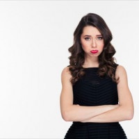 Cute offended sad curly girl with bright makeup in retro style standing with arms crossed over white background