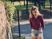 Beautiful woman with long blond curly hair. Woman in checkered shirt and blue jeans