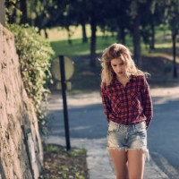 Beautiful woman with long blond curly hair. Woman in checkered shirt and blue jeans