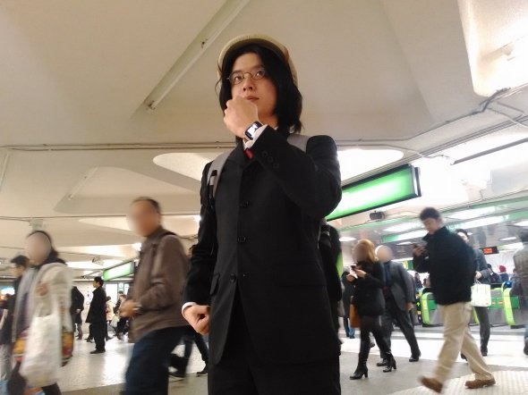西口改札前で、リモートカメラを使いながら自撮り撮影を行う筆者。通り過ぎる人が思いっきり「なんだこいつ」的な目で見ているのがつらい