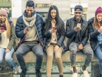 Multicultural group of friends using cellphones - Students sitting in a row and typing on the smartphones