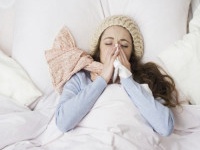 Sick woman with thermometer is lying in bed. She has cold, flu and high fever.