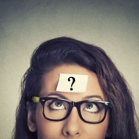 thinking woman with question mark on gray wall background