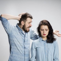 The young couple with different emotions during conflict on gray background