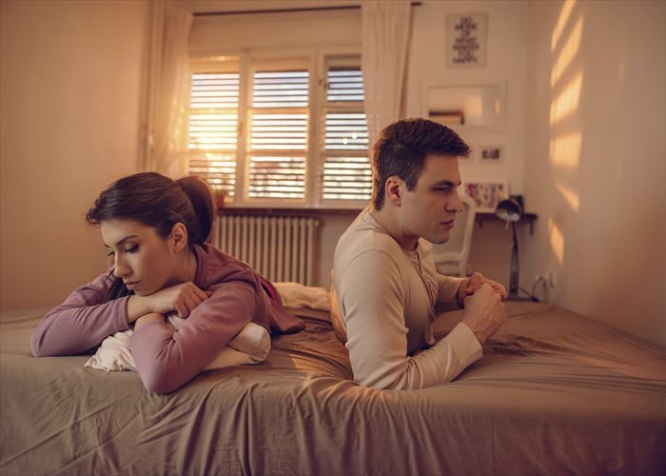 Young depressed couple being angry with each other and lying back to back on the bed.
