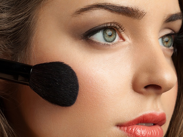 Woman face powders, and apply blush to the cheekbones