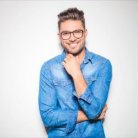 beautiful young man wearing glasses, smiling and touching his chin