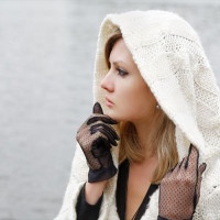 The thoughtful girl in  knitted dress on a background of water