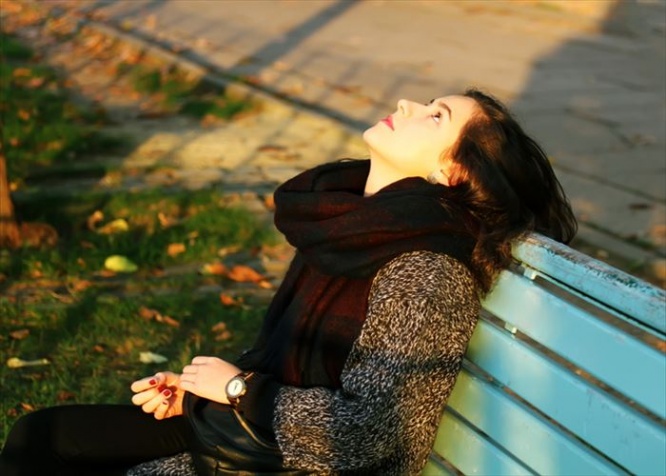 Girl sitting on the bench in the autumn in park