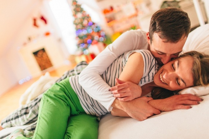 Lovely couple in pyjamas is spending Christmas morning in their warm bed