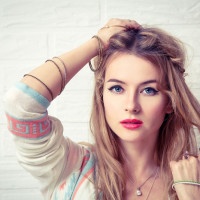 Boho Girl Portrait at White Brick Wall Background. Bohemian Fashion Woman Portrait. Toned Photo with Copy Space.