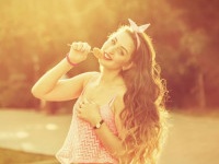 Hipster girl with a lollipop and long hair. Photo at sunset. Warm toning. Concept Pin-up girl style. Soft focus.