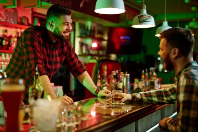 Happy barman talking to client in bar