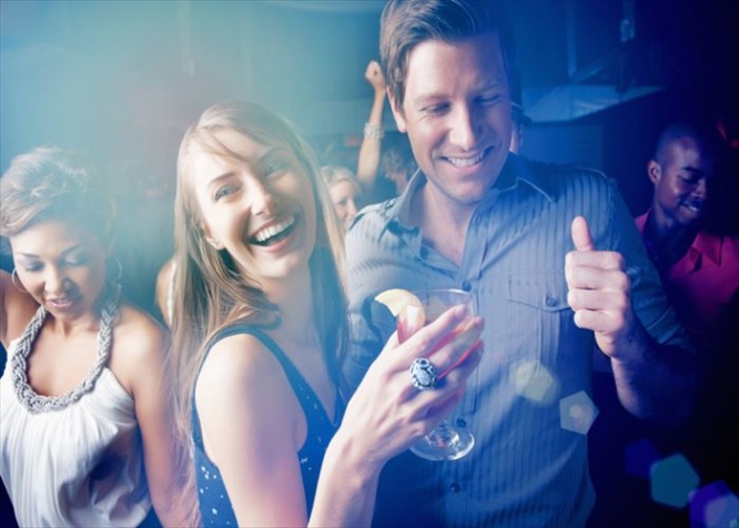 Group of young boys and girls dancing while enjoying at pub