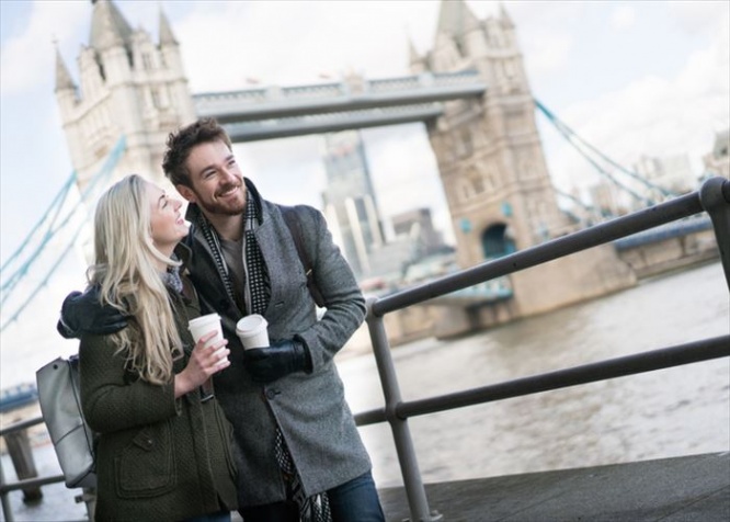Happy couple on a date walking around London drinking a cup of coffee to go