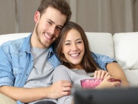 Happy couple watching movie on tv