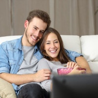 Happy couple watching movie on tv