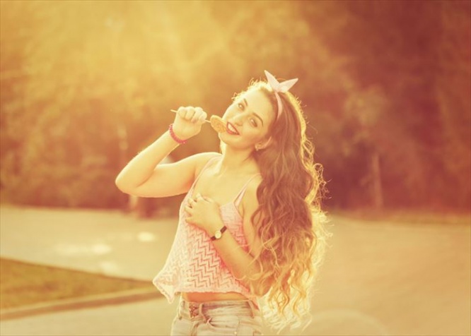 Hipster girl with a lollipop and long hair. Photo at sunset. Warm toning. Concept Pin-up girl style. Soft focus.