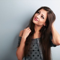 Confusion fashion makeup brunette woman thinking and looking up on blue copy space background