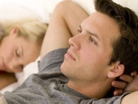 Couple in bed, man looking worried