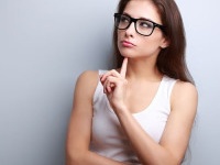 Beautiful serious thinking young woman looking up on empty copy space