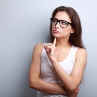 Beautiful serious thinking young woman looking up on empty copy space
