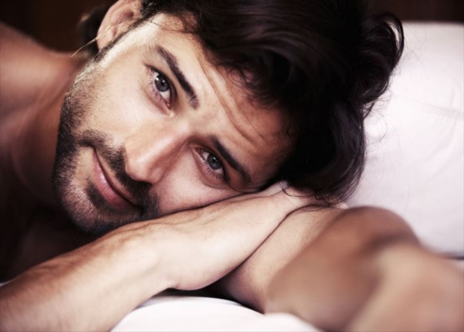 Young sexy male lying in bed and looking towards the camera - closeup