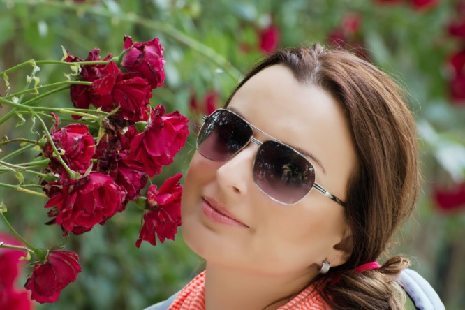 Beautiful woman in garden with red roses