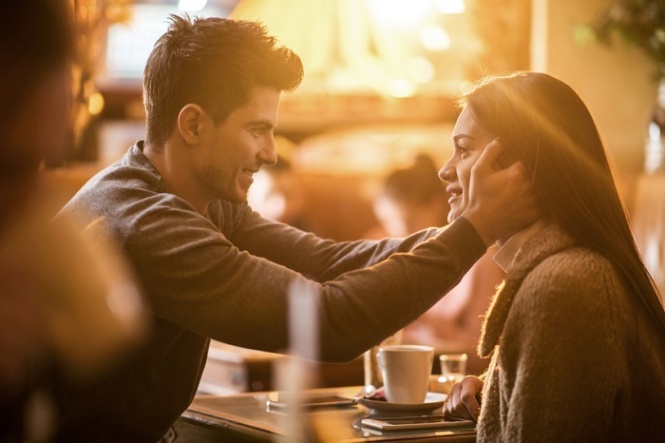 Affectionate man sitting in a cafe with his girlfriend and expressing his love on a romantic way.