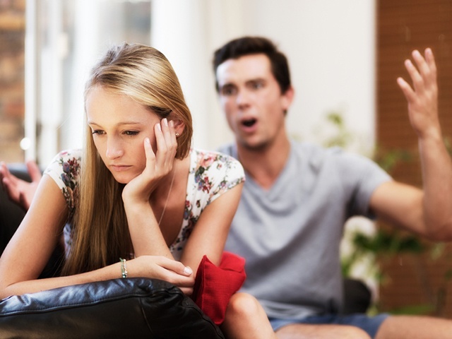 Couple argue; she looks depressed, he seems irritated and aggressive