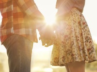 Young couple in love walking in the autumn park holding hands looking in the sunset