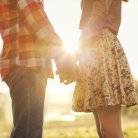 Young couple in love walking in the autumn park holding hands looking in the sunset