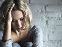 A pretty young blonde woman sitting down while looking severely depressed